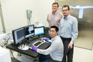 ORNL’s Yang Song (seated), Dale Hensley (standing left) and Adam Rondinone examine a carbon nanospike sample with a scanning electron microscope.